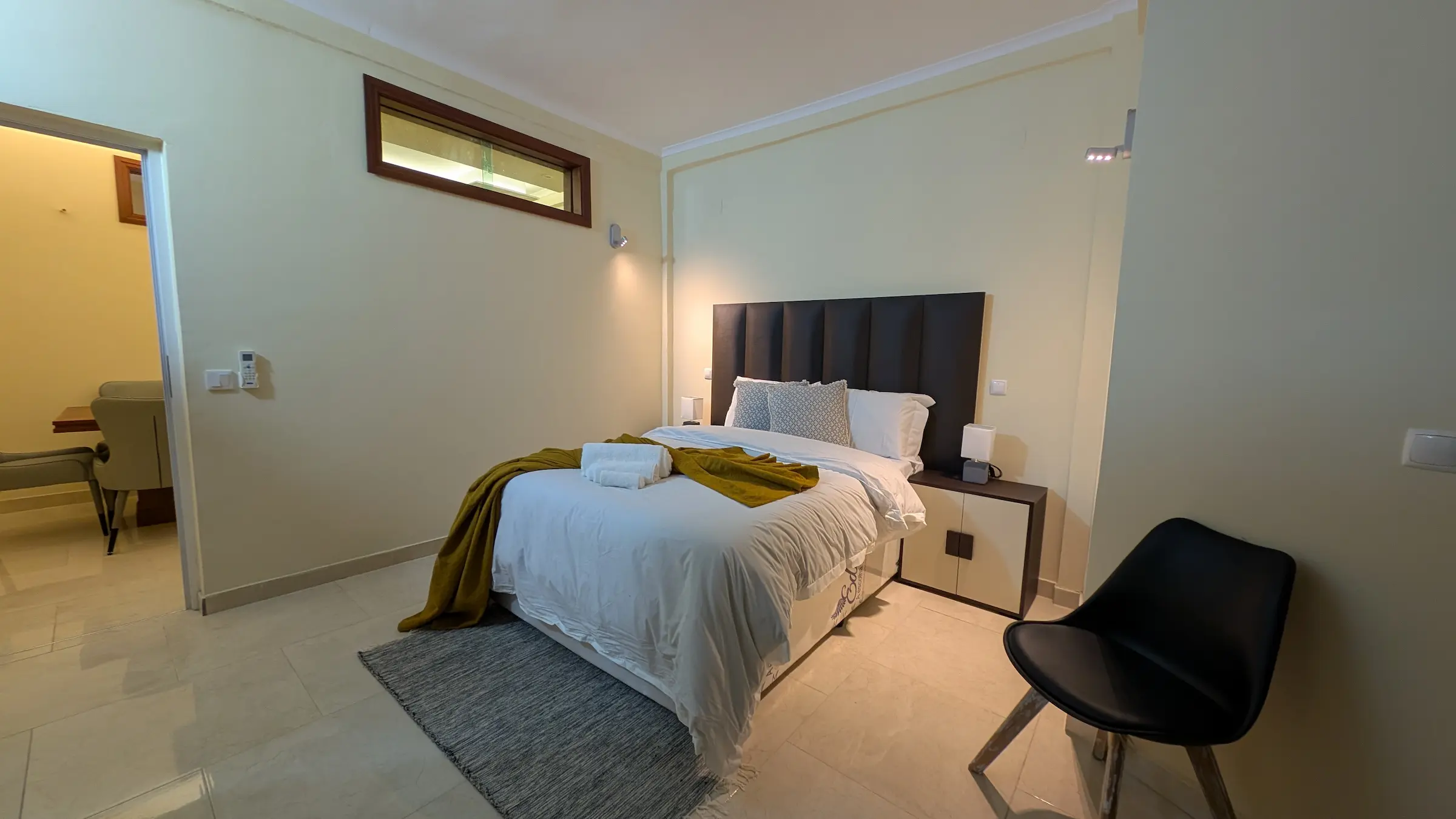 Cozy bedroom with a neatly made bed and a black chair.