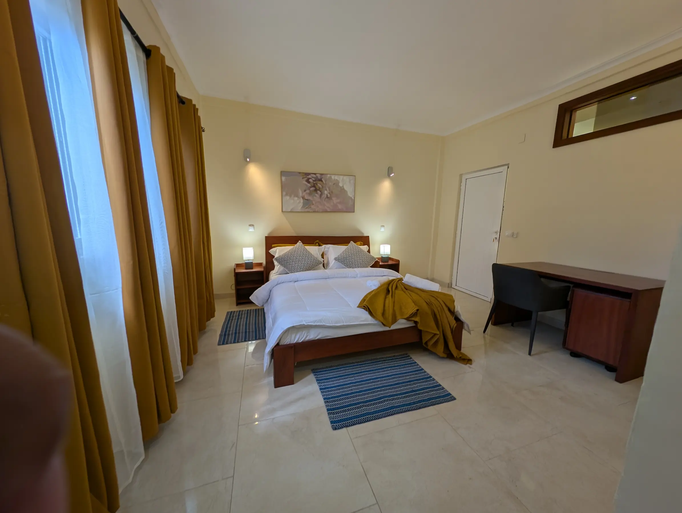 Suite with wooden bed and yellow curtains.